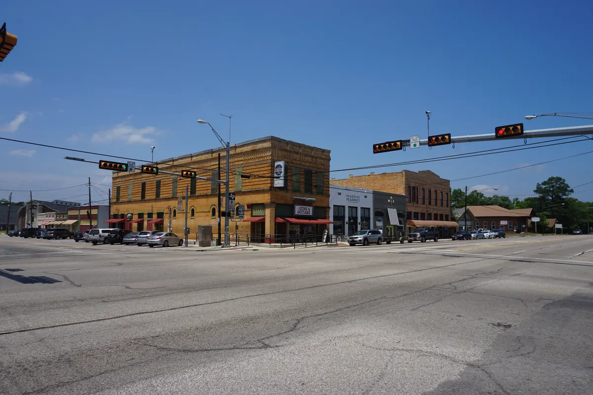 Two-story brick buildings at the corner of Hubbard Street and Main Street in downtown Lindale, under traffic signals.